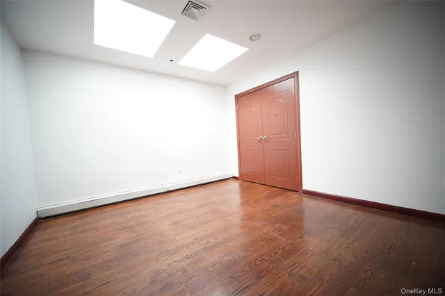an empty room with wooden floor and fan