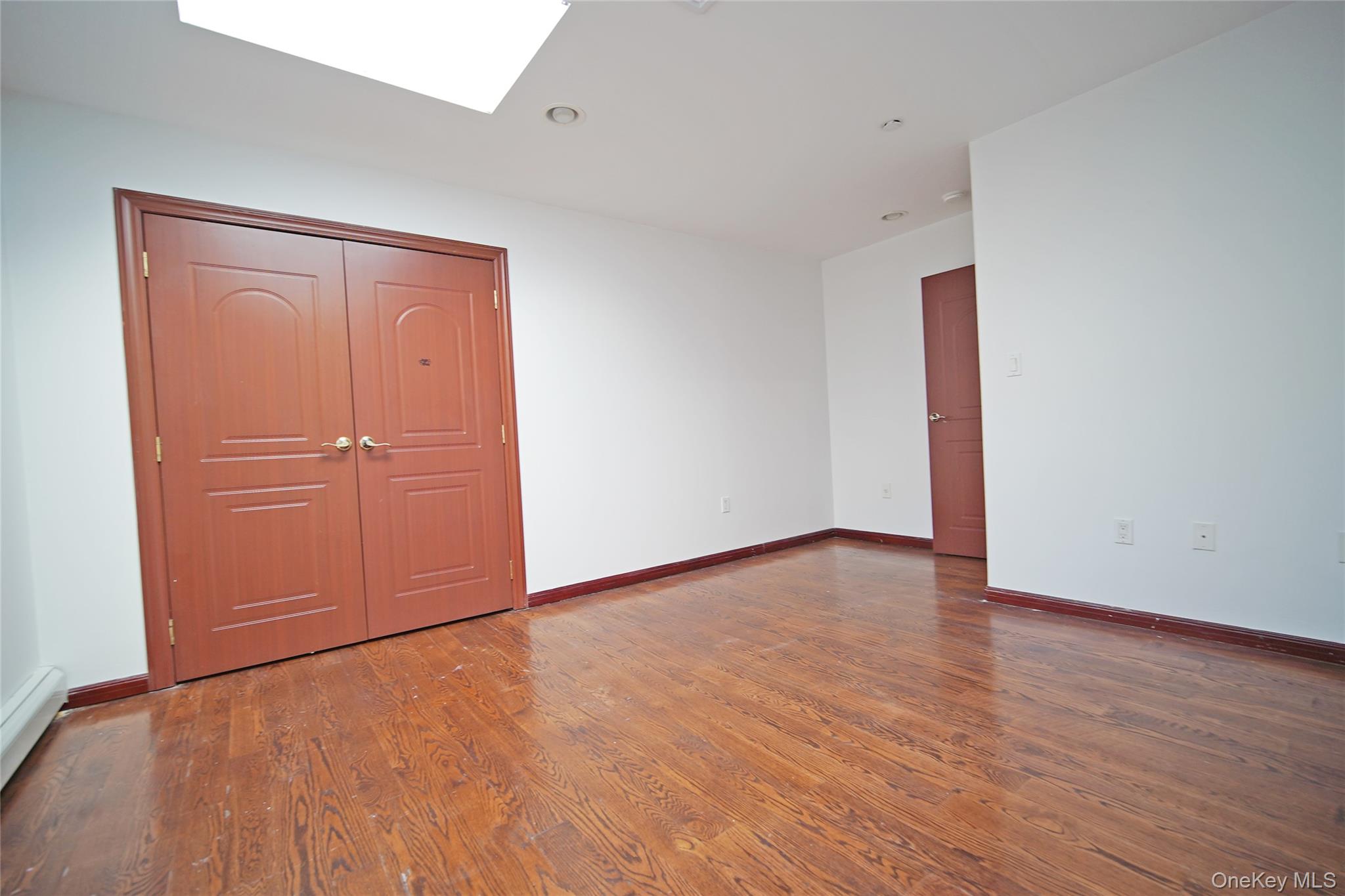 931 East 215th Street, Unit 2 Bronx, NY 10469 - Photo 12 of 16 an empty room with wooden floor and cabinet