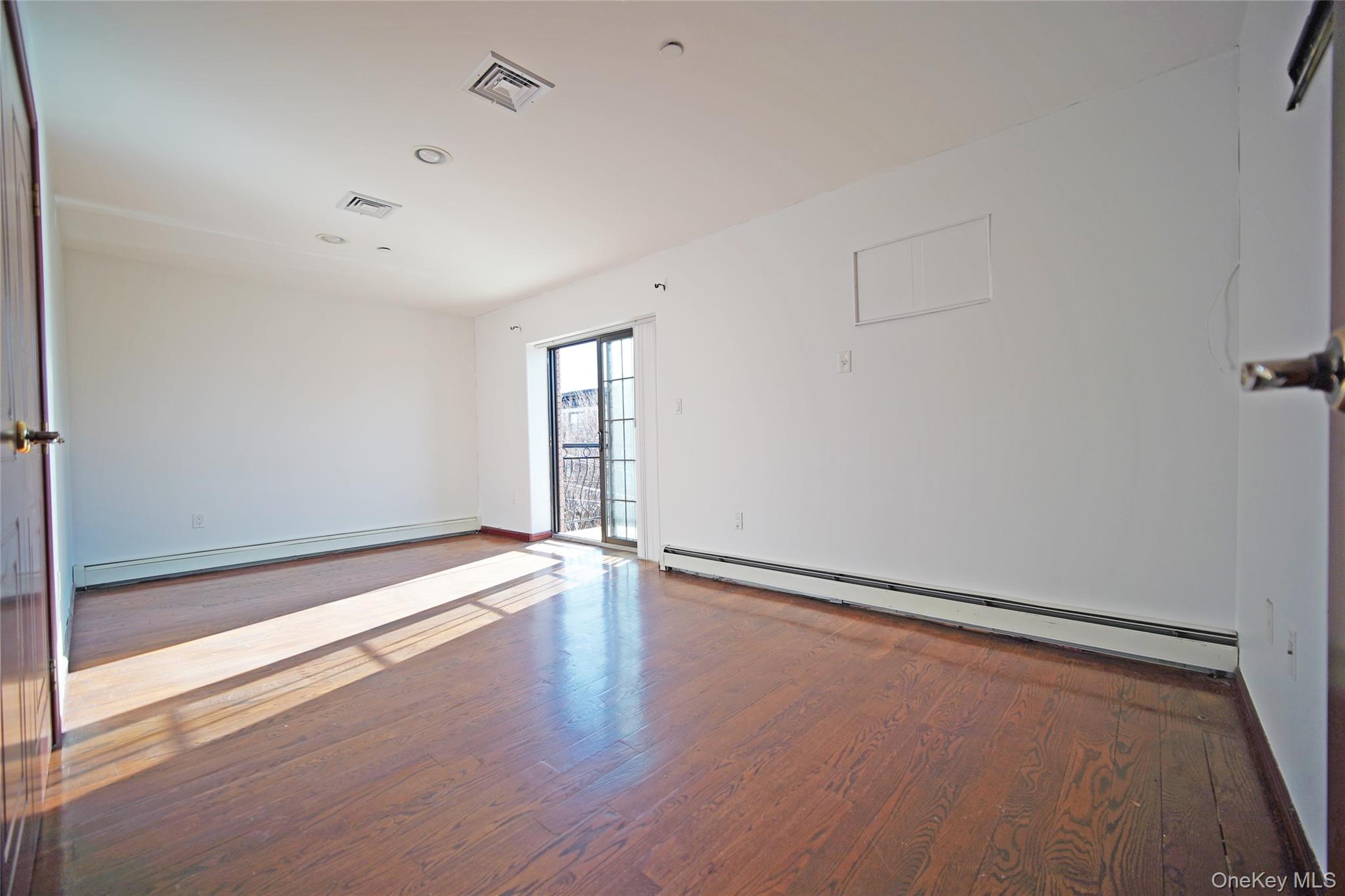 931 East 215th Street, Unit 2 Bronx, NY 10469 - Photo 13 of 16 a view of an empty room with wooden floor and a window
