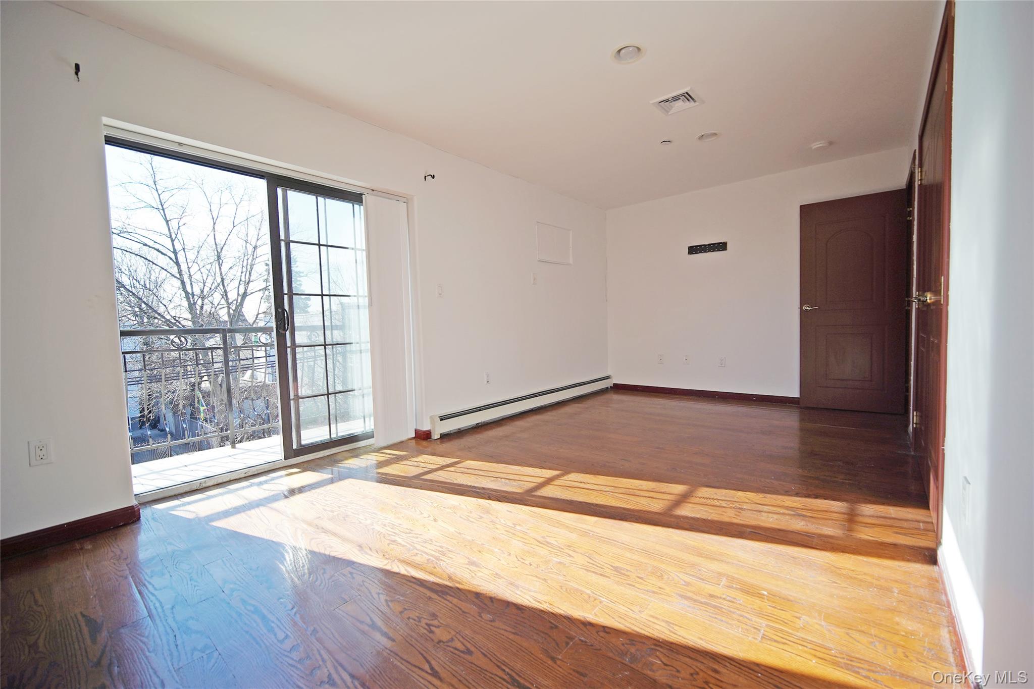 931 East 215th Street, Unit 2 Bronx, NY 10469 - Photo 14 of 16 a view of an empty room with wooden floor and a window