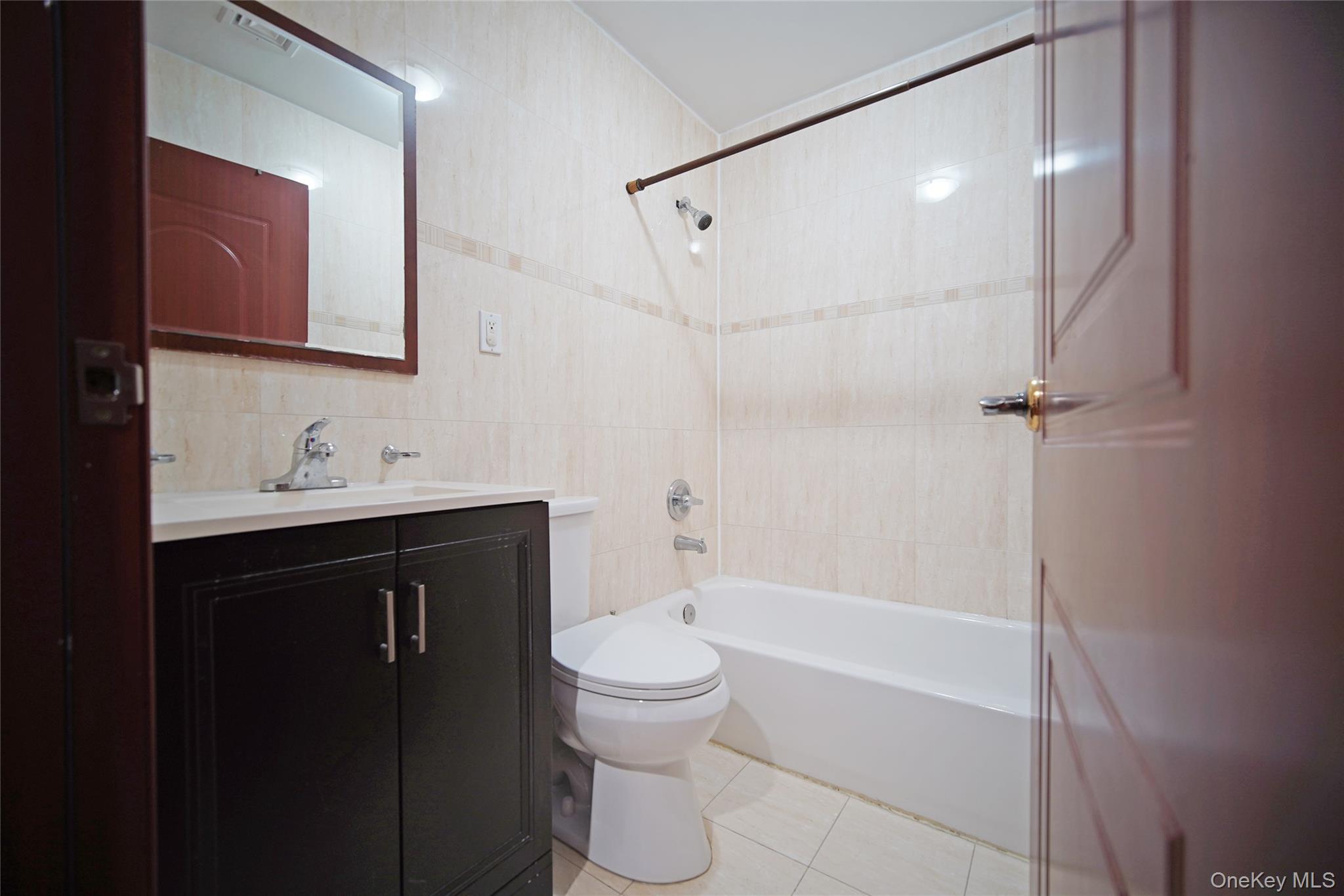 931 East 215th Street, Unit 2 Bronx, NY 10469 - Photo 9 of 16 a bathroom with a bathtub shower sink vanity and toilet