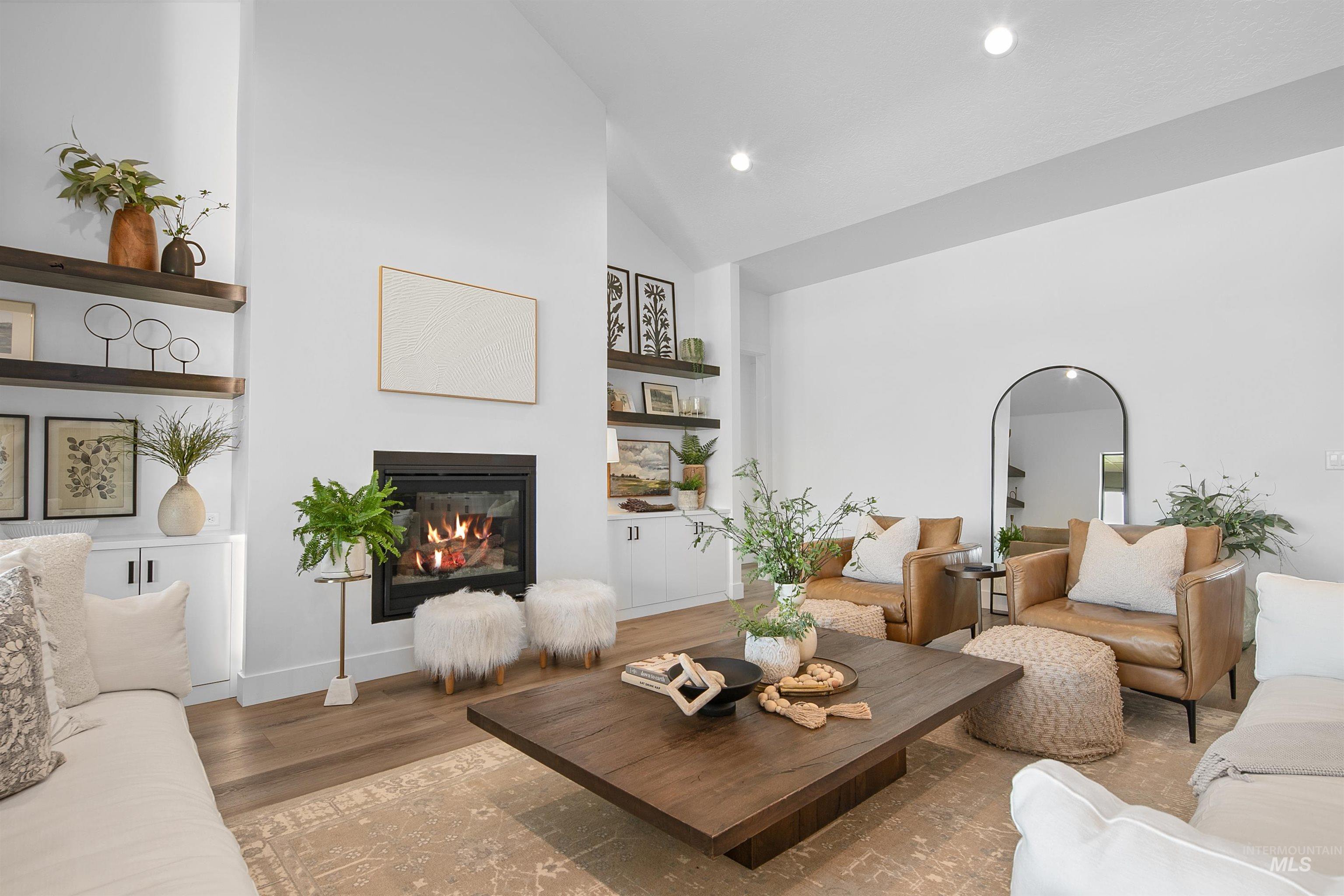 23910 Timber Hls Road Caldwell, ID 83607 - Photo 12 of 50 Living area featuring wood finished floors, high vaulted ceiling, a glass covered fireplace, built in shelves, and recessed lighting