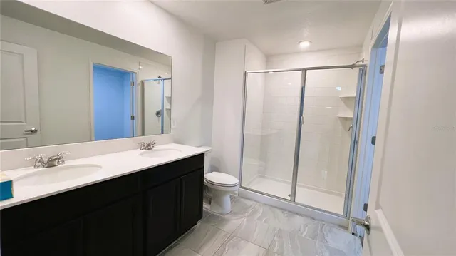 a bathroom with a double vanity sink toilet and shower