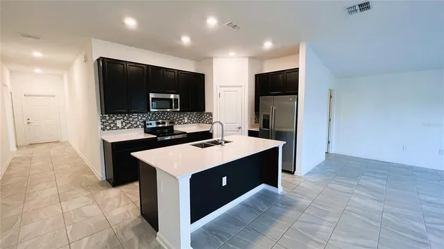 a kitchen with stainless steel appliances a stove top oven refrigerator a sink and a refrigerator