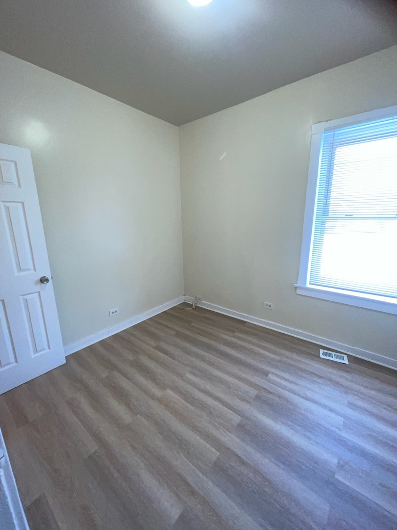 714 West 80th Street, Unit 1 Chicago, IL 60620 - Photo 9 of 10 an empty room with wooden floor and windows