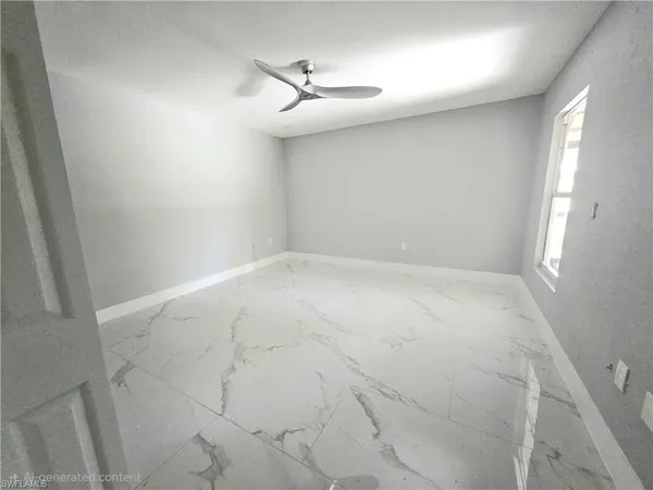 an empty room with a chandelier fan and windows