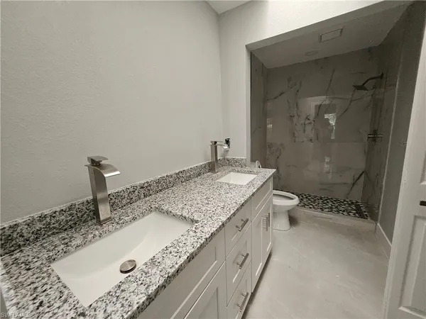 a bathroom with a granite countertop sink a toilet and shower