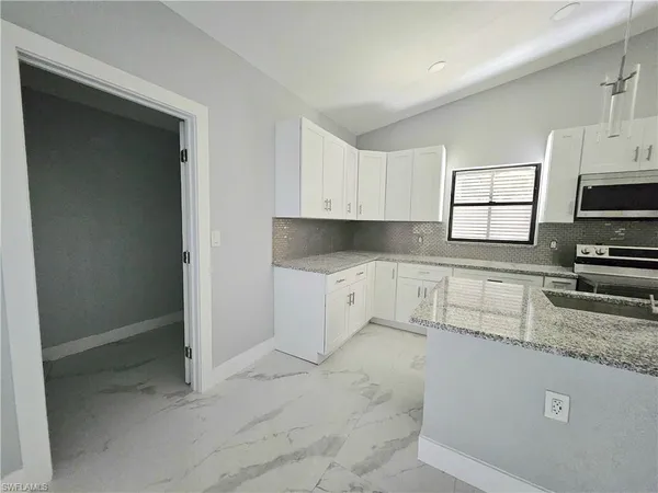 a kitchen with granite countertop a stove a sink and a microwave