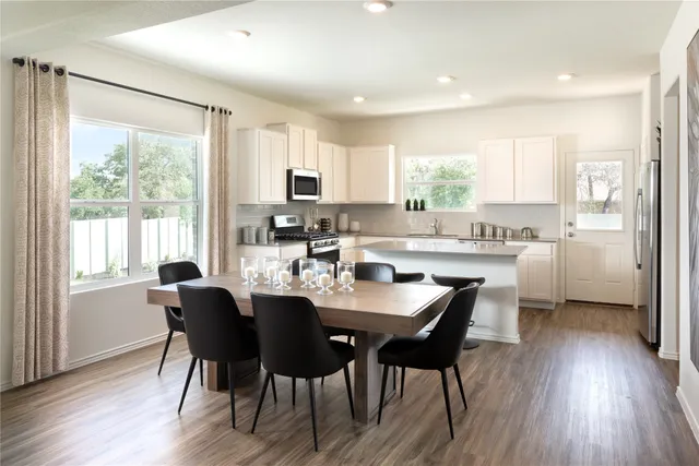 a kitchen with kitchen island a dining table and chairs
