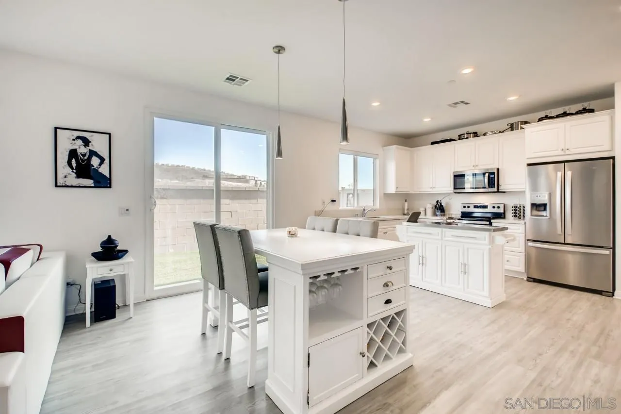 10633 Busch Street Spring Valley, CA 91978 - Photo 12 of 28 a kitchen with a stove a refrigerator and a dining table with wooden floor