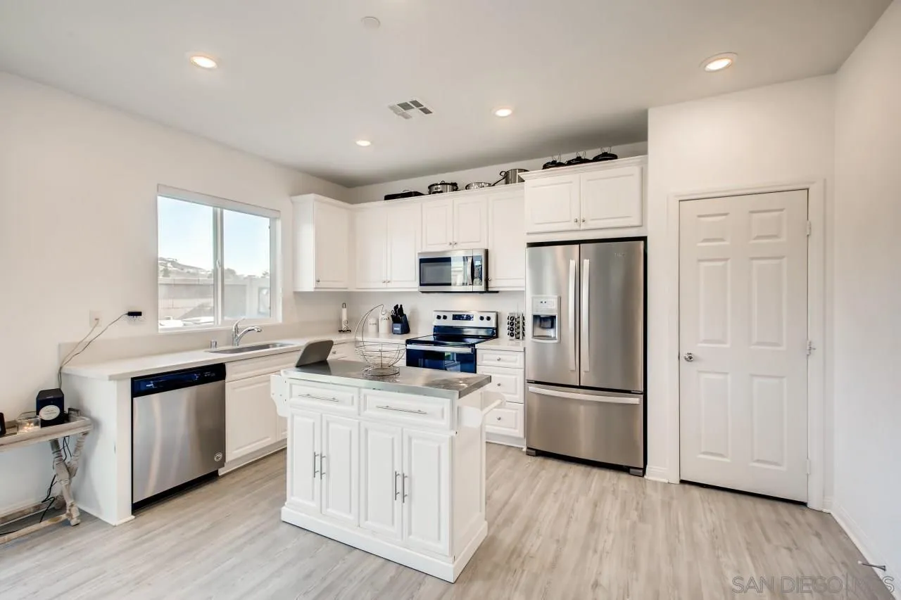 10633 Busch Street Spring Valley, CA 91978 - Photo 13 of 28 a kitchen with stainless steel appliances granite countertop a refrigerator a stove a sink dishwasher and a refrigerator with wooden floor