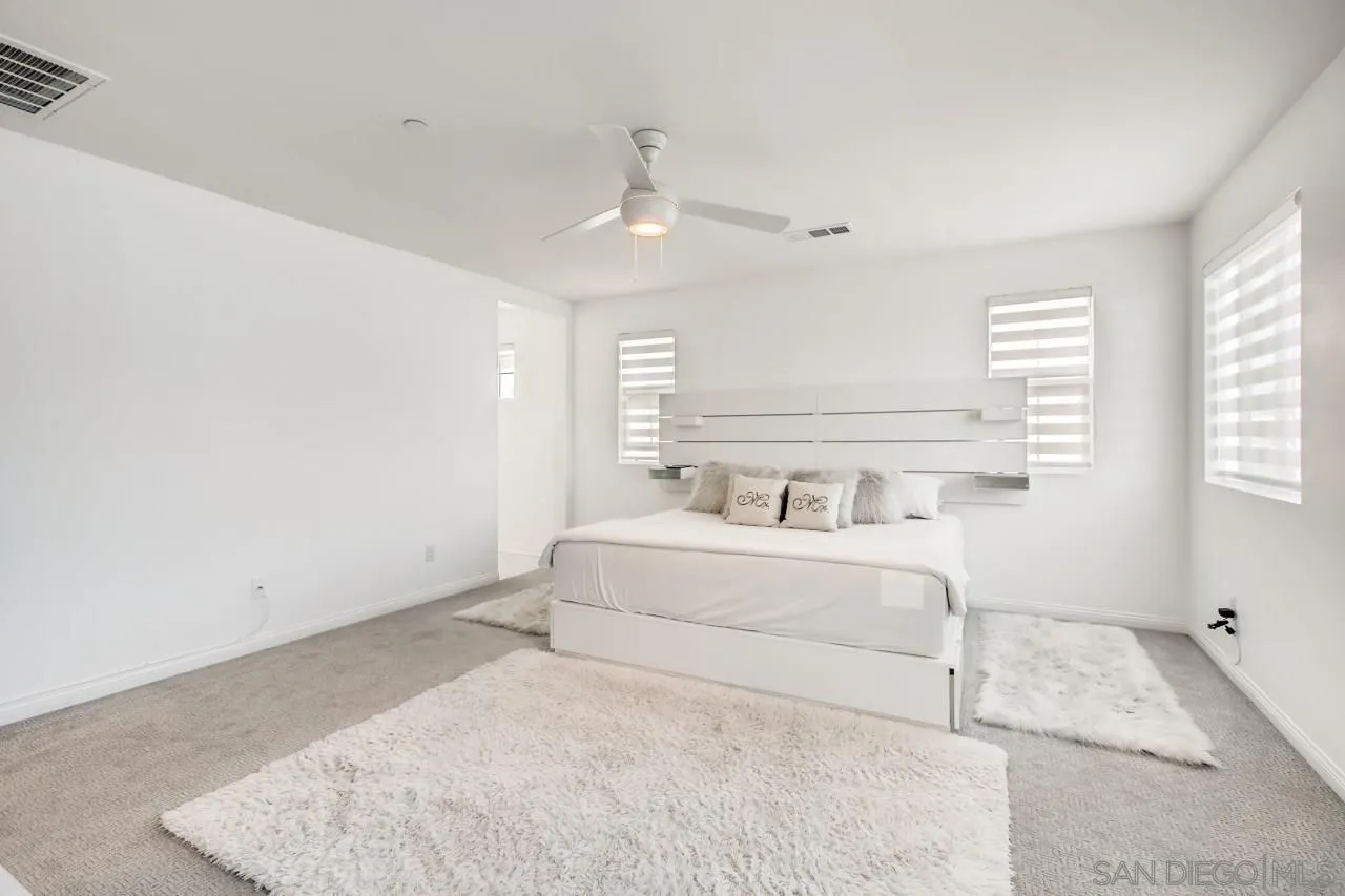 10633 Busch Street Spring Valley, CA 91978 - Photo 17 of 28 a spacious bedroom with a bed a rug and windows