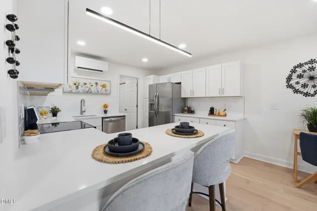 a kitchen with sink a stove and white cabinets with wooden floor