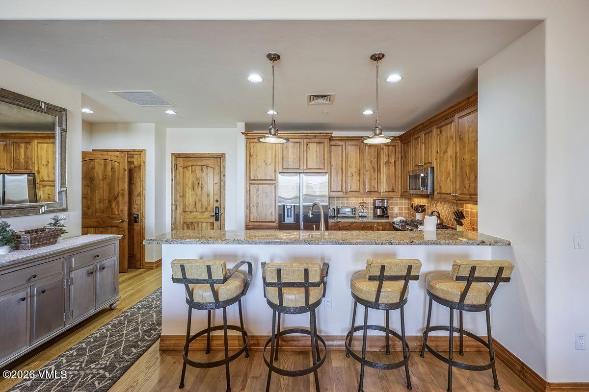 300 Prater Road, Unit A408 Beaver Creek, CO 81620 - Photo 7 of 31 a kitchen with granite countertop a dining table chairs cabinets wooden floor and appliances