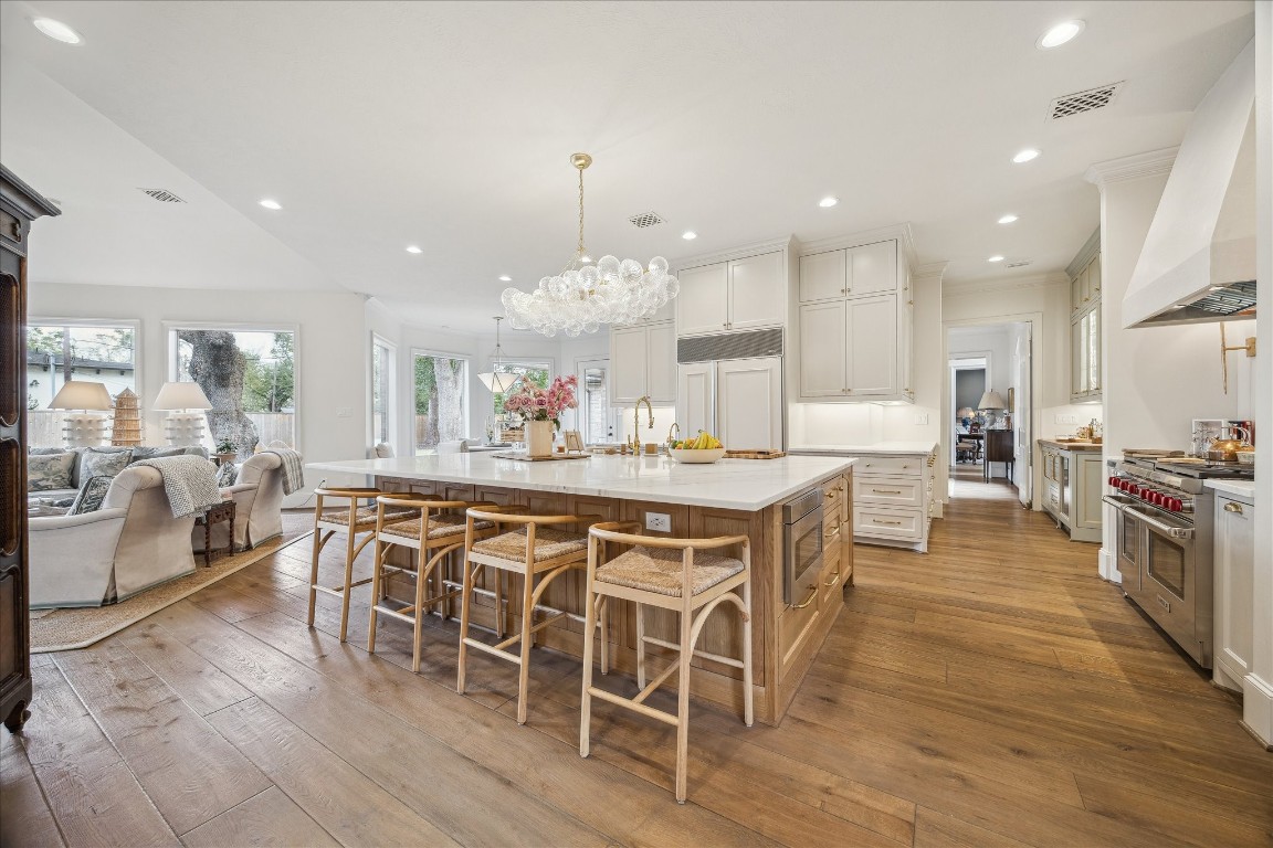 11524 Taylorcrest Road Houston, TX 77024 - Photo 21 of 47 A large 7' x 10' white oak island anchors the kitchen with ample counter seating is illuminated above by a Julie Neill Talia large linear “bubble” chandelier.