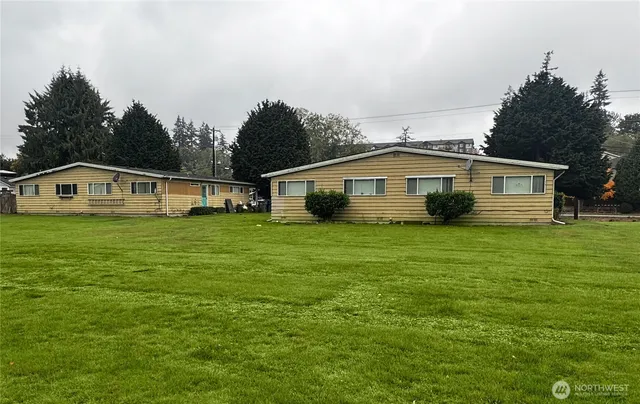 a view of house with a big yard and large trees