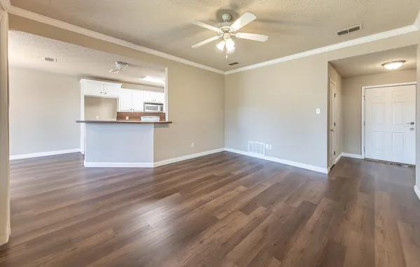 a view of a room with wooden floor and a ceiling fan