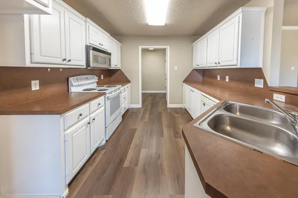 a kitchen with granite countertop a sink and dishwasher a stove top oven with wooden floor