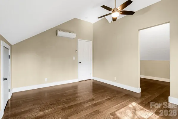 an empty room with wooden floor and a ceiling fan