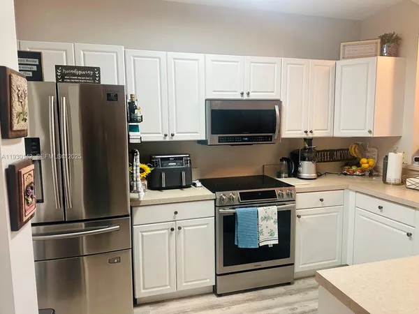 a kitchen with stainless steel appliances white cabinets white stove a refrigerator and a microwave