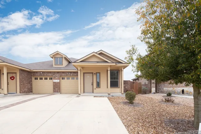 a view of a white house with a large tree and plants