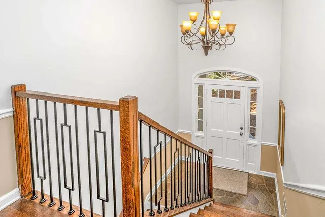 a view of staircase with railing and a chandelier