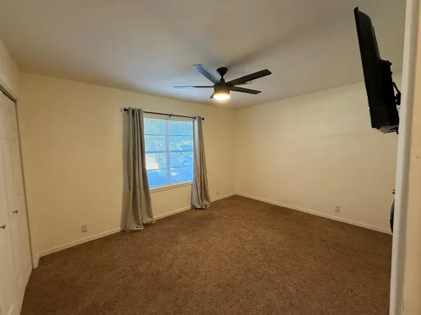 an empty room with windows and fan