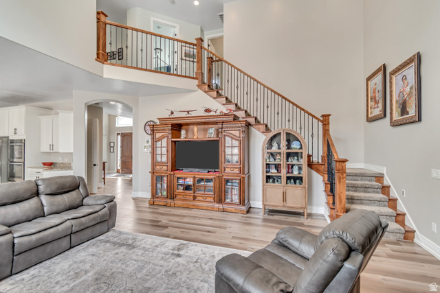 2543 East 700 South Springville, UT 84663 - Photo 32 of 73 Living area featuring arched walkways, light wood-style floors, and a high ceiling