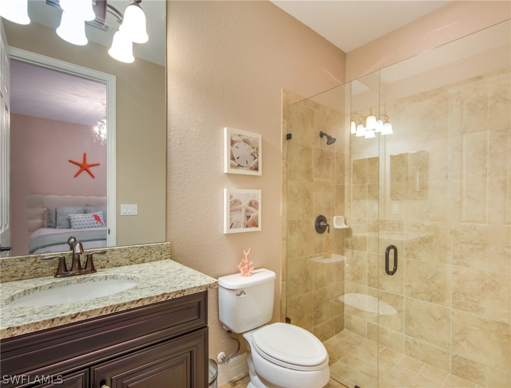 9495 Piacere Way Naples, FL 34113 - Photo 19 of 25 a bathroom with a granite countertop sink a toilet a mirror and shower