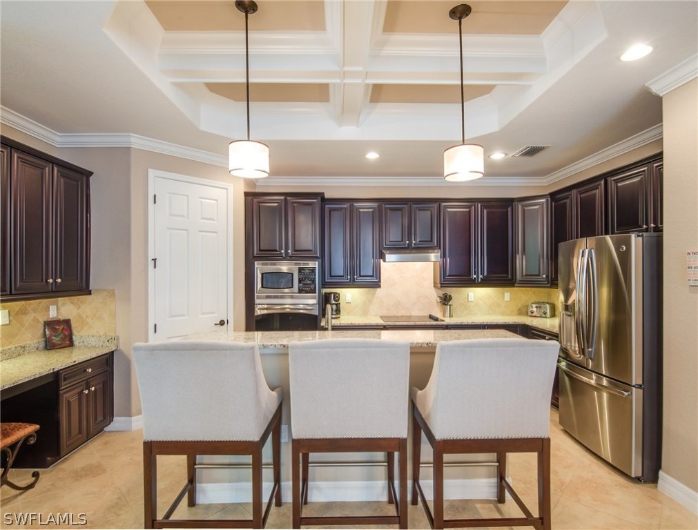 9495 Piacere Way Naples, FL 34113 - Photo 9 of 25 a kitchen with a refrigerator a sink and chairs