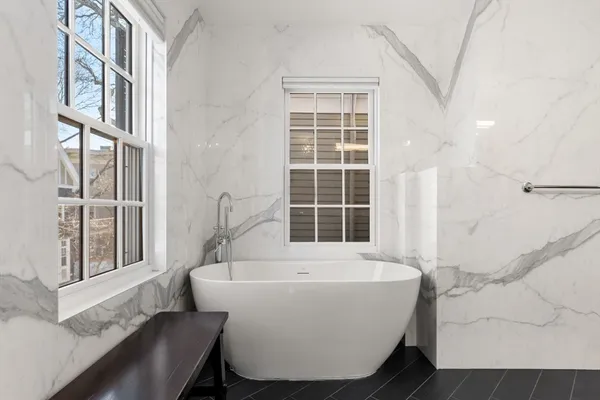 a white bath tub sitting in a bathroom next to a window
