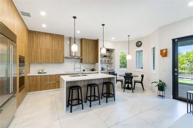 a kitchen with kitchen island granite countertop a sink a stove a dining table and chairs