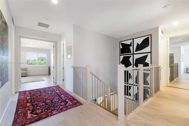 a view of a hallway to room with wooden floor and windows