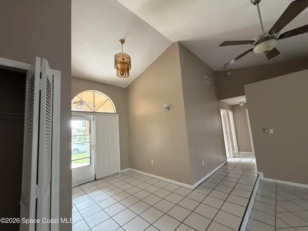 a view of a livingroom with a window and a chandelier fan