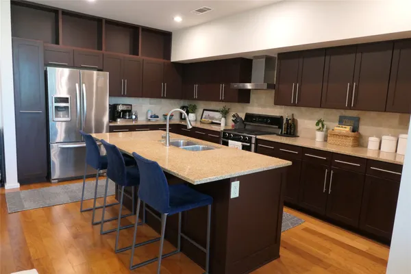 a kitchen with stainless steel appliances a sink a stove a refrigerator cabinets and a kitchen island