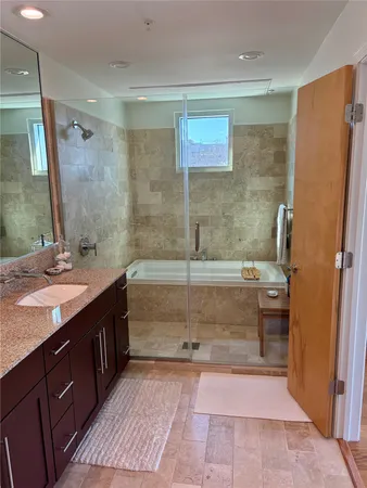 a bathroom with a granite countertop sink a mirror and a bathtub