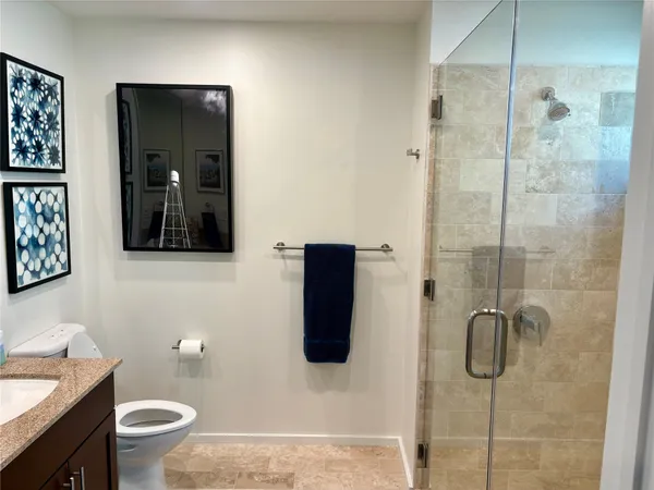 a bathroom with a granite countertop shower and a toilet