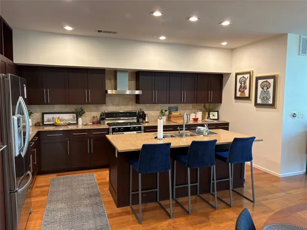 a kitchen with stainless steel appliances granite countertop a table chairs sink refrigerator and cabinets