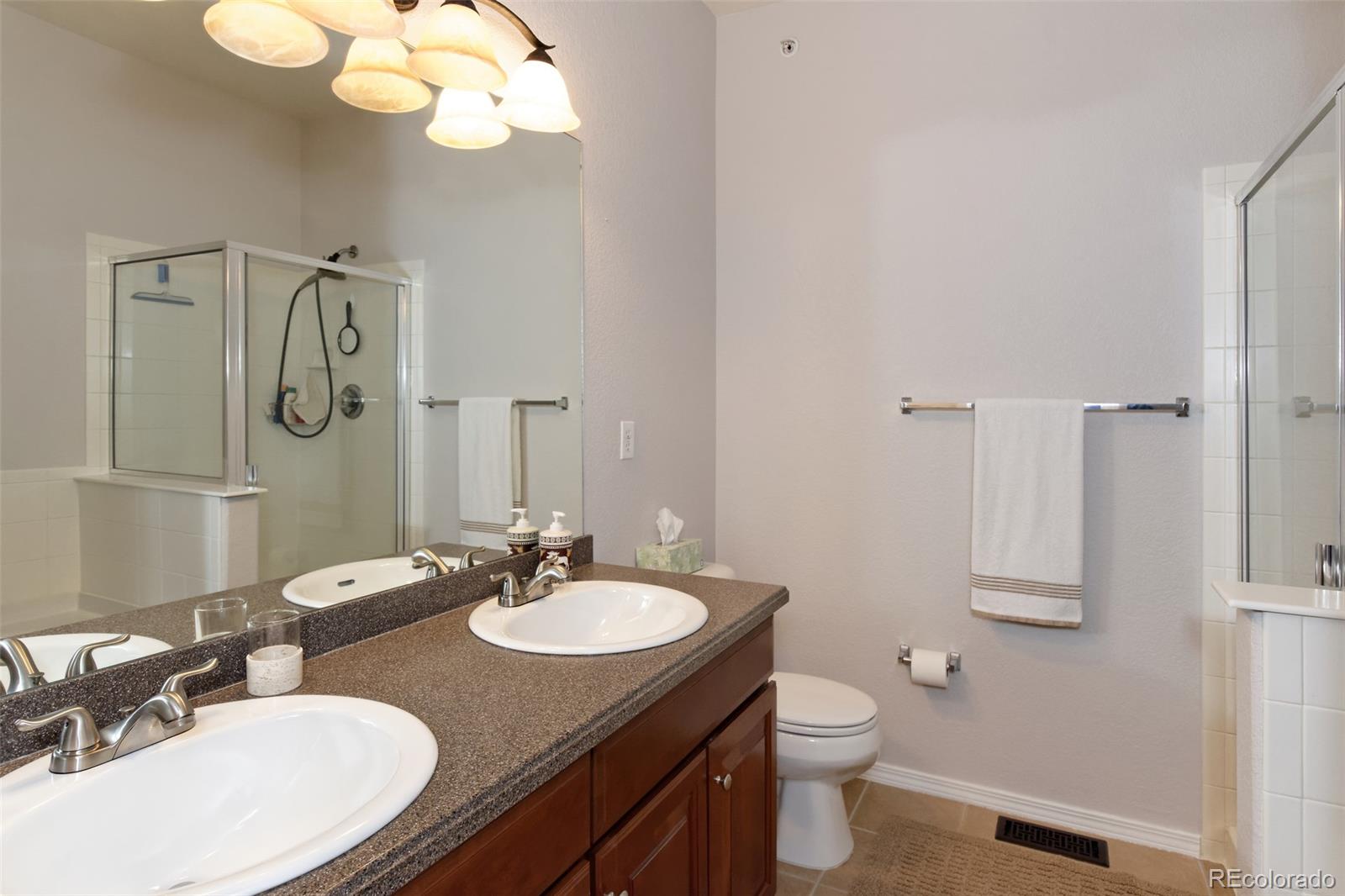 8440 Canyon Rim Trail, Unit 4 Parker, CO 80134 - Photo 15 of 28 a bathroom with a granite countertop sink a toilet and a mirror