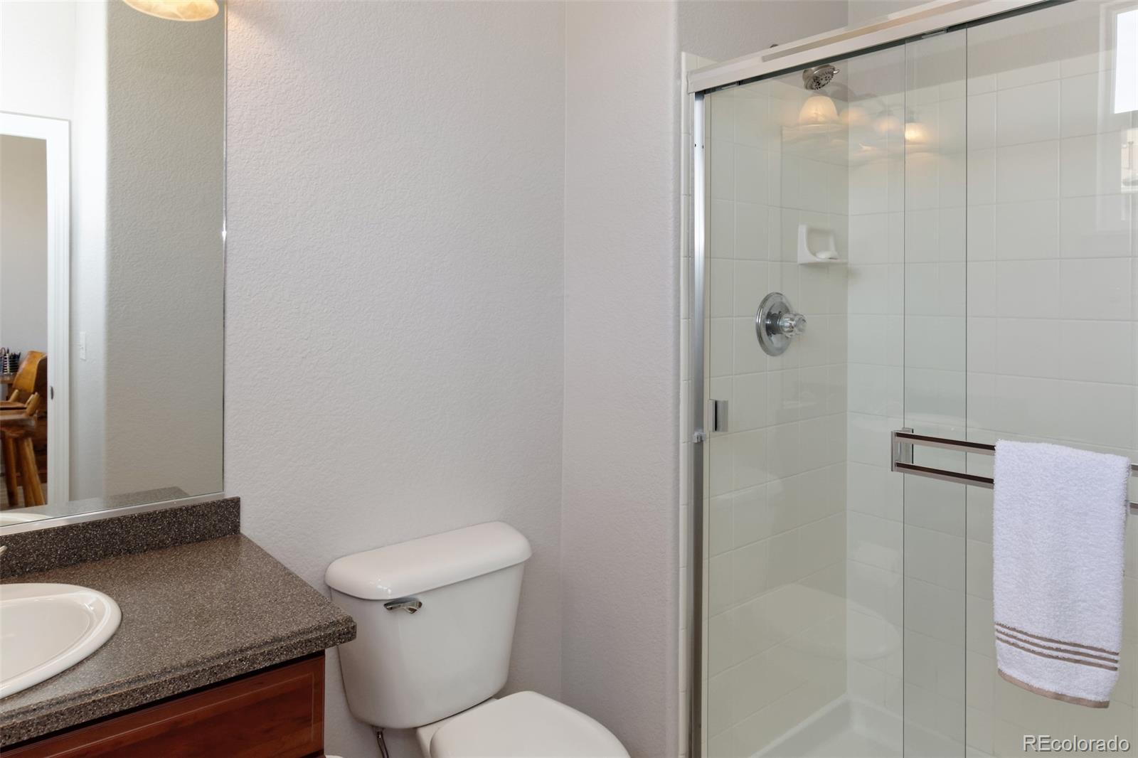 8440 Canyon Rim Trail, Unit 4 Parker, CO 80134 - Photo 25 of 28 a bathroom with a granite countertop sink toilet and shower
