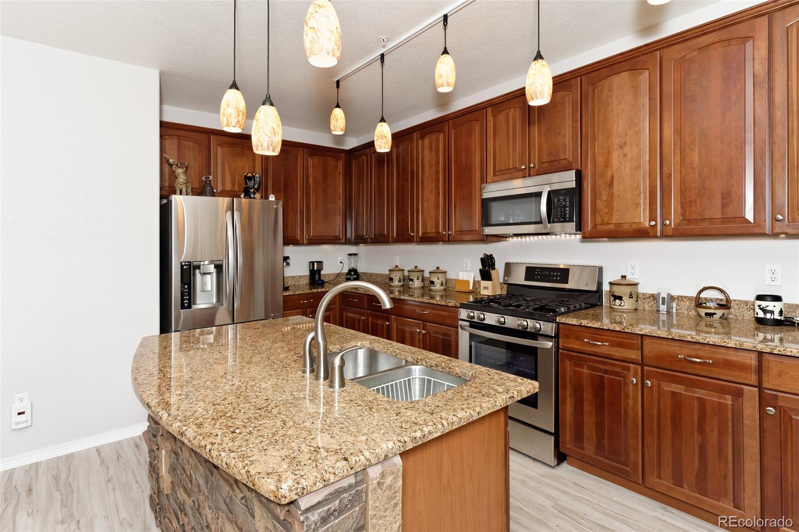 8440 Canyon Rim Trail, Unit 4 Parker, CO 80134 - Photo 3 of 28 a kitchen with stainless steel appliances granite countertop a stove top oven a refrigerator and a center island