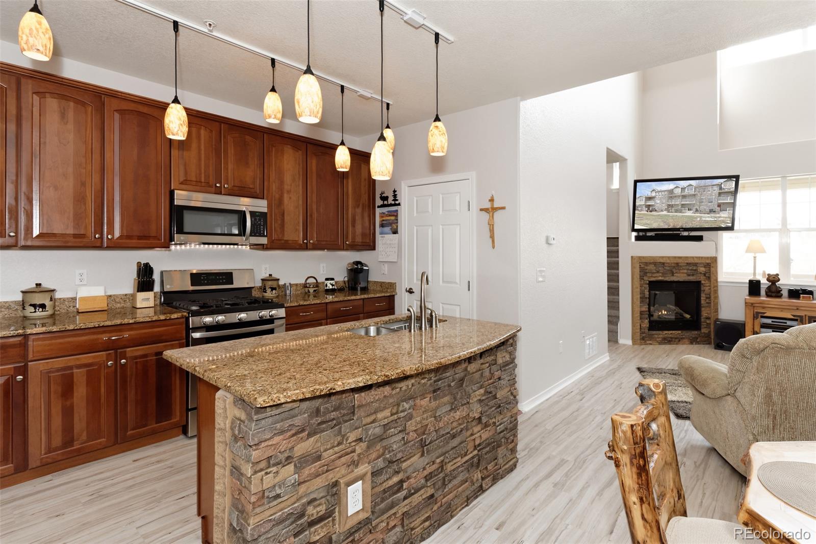 8440 Canyon Rim Trail, Unit 4 Parker, CO 80134 - Photo 5 of 28 a kitchen with kitchen island granite countertop wooden cabinets a stove a sink and a oven