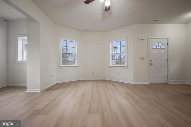 an empty room with wooden floor chandelier and windows