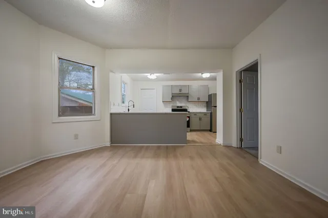 a big room with wooden floor and kitchen view