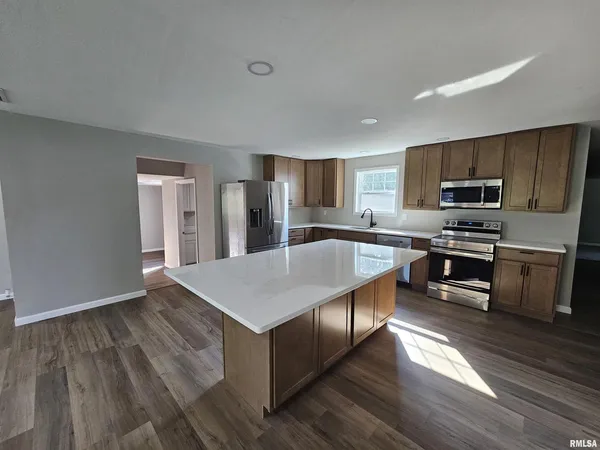 a kitchen with stainless steel appliances a stove a sink a refrigerator white cabinets and wooden floor