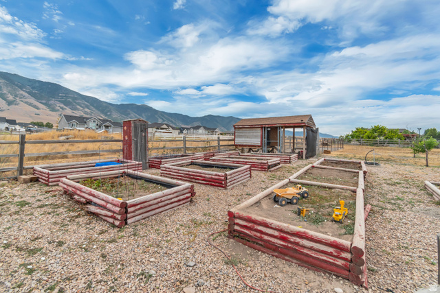 7296 Ridge Road Lake Point, UT 84074 - Photo 8 of 54 Multiple raised garden beds, a rustic storage shed, and a wooden fence define this outdoor space