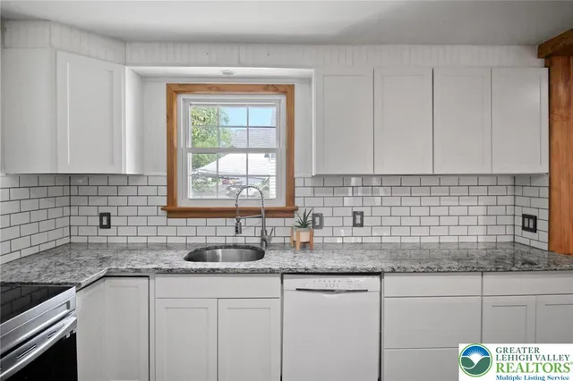a view of an empty room with a window and a kitchen