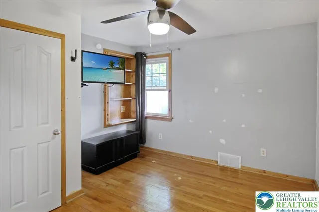 a view of an empty room with window and wooden floor