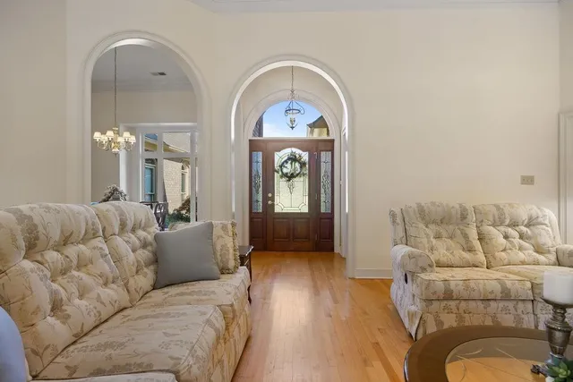 a living room with furniture a large window and wooden floors