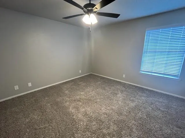 an empty room with a window and a fan